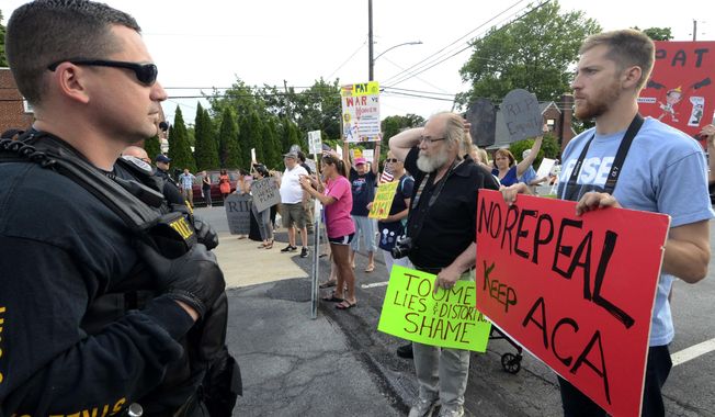 Watched by police, demonstrators against the Senate Republican health care bill await the arrival of Pennsylvania&#x27;s U.S. Sen. Pat Toomey outside the studios of WHTM-TV, Wednesday, July 5, 2017 in Harrisburg, Pa. Toomey took questions in front of a live audience in public for the first time this year. (AP Photo/Marc Levy)