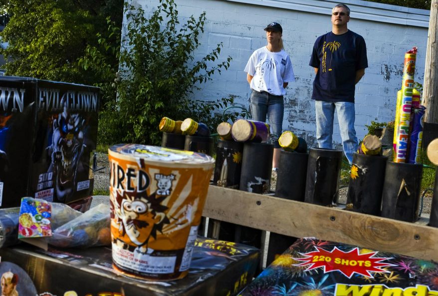 In this June 28, 2017 photo, from left, Bethany Bateman and Mike Bateman, members of the Pennsylvania Pyrotechnics Artists, pose with a small collection of consumer-grade fireworks used in some of their shows near their home in Greensburg, Pa.(Christian Tyler Randolph/Pittsburgh Tribune-Review via AP)