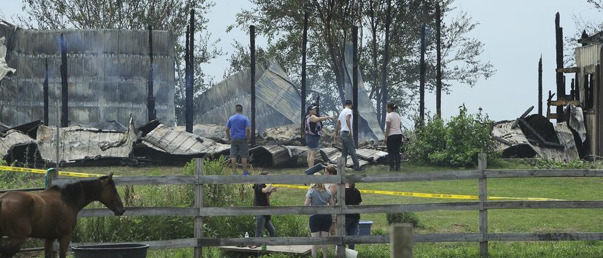 Horse owners from around the area tend to the horses that survived a massive stable fire at Del Real Stables early Wednesday, July 5, 2017 outside of Plainfield, Ill. The stable fire claimed at least 18 horse. Firefighters from eight other departments assisted, said Mary Kay Ludemann, fire marshal for the Plainfield Fire Protection District. She said the barn is a “total loss.” (Mark Welsh/Daily Herald via AP)