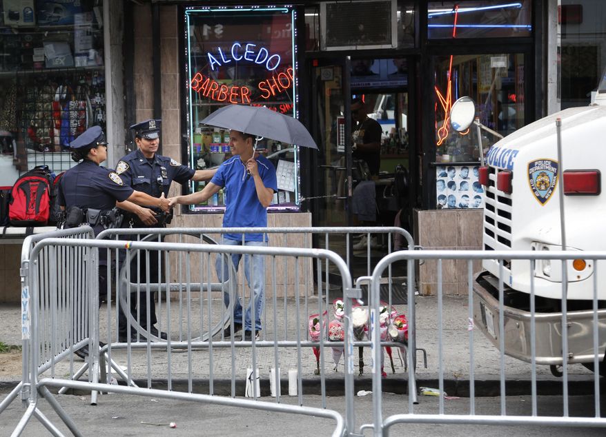 A man who left flowers near the site where a police officer was killed shakes hands with police officers working in the Bronx section of New York, Thursday, July 6, 2017. Police officer Miosotis Familia was shot to death early Wednesday, ambushed inside her command post by an ex-convict, authorities said. He was later killed after pulling a gun on police. (AP Photo/Seth Wenig)