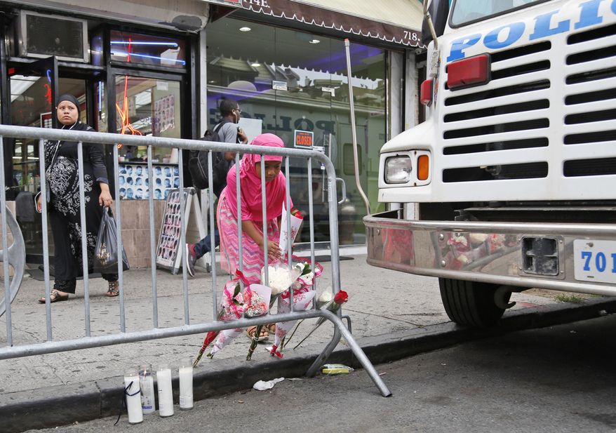 Haniya Smith, a local resident, leaves flowers near the site where a police officer was killed in the Bronx section of New York, Thursday, July 6, 2017. Police officer Miosotis Familia was shot to death early Wednesday, ambushed inside her command post by an ex-convict, authorities said. He was later killed after pulling a gun on police. (AP Photo/Seth Wenig)