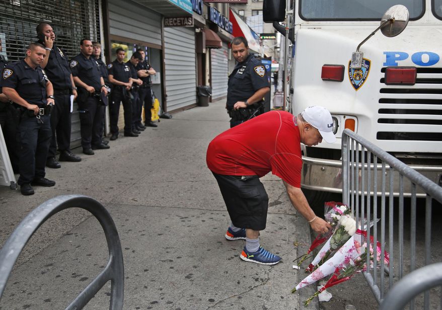A man leaves flowers near the site where a police officer was killed in the Bronx section of New York, Thursday, July 6, 2017. Police officer Miosotis Familia was shot to death early Wednesday, ambushed inside her command post by an ex-convict, authorities said. He was later killed after pulling a gun on police. (AP Photo/Seth Wenig)