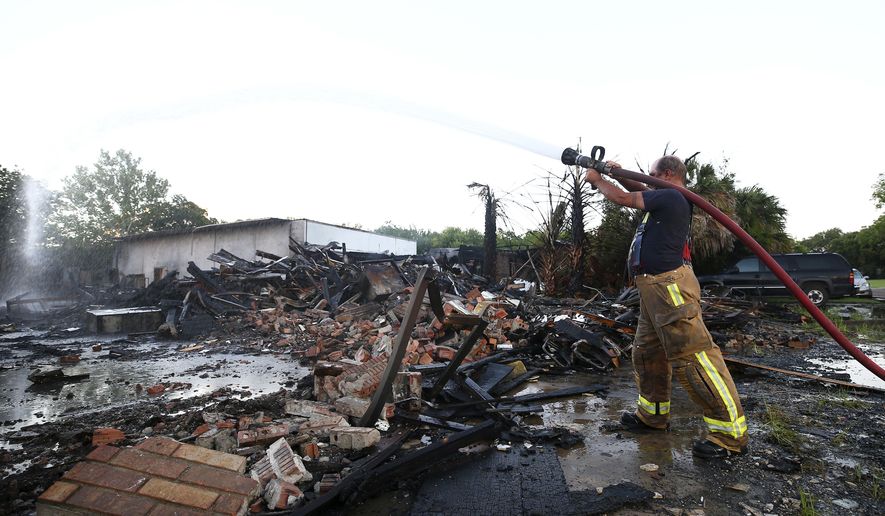 South Houston volunteer firefighter Robert Kyle douses hot spots remaining from a two-alarm fire that destroyed a two-story warehouse on North 1st Street near Spencer Highway Thursday, July 6, 2017, in South Houston. The flames from the fire blew out a transformer, leaving people in the area without power. (Godofredo A. Vasquez/Houston Chronicle via AP)