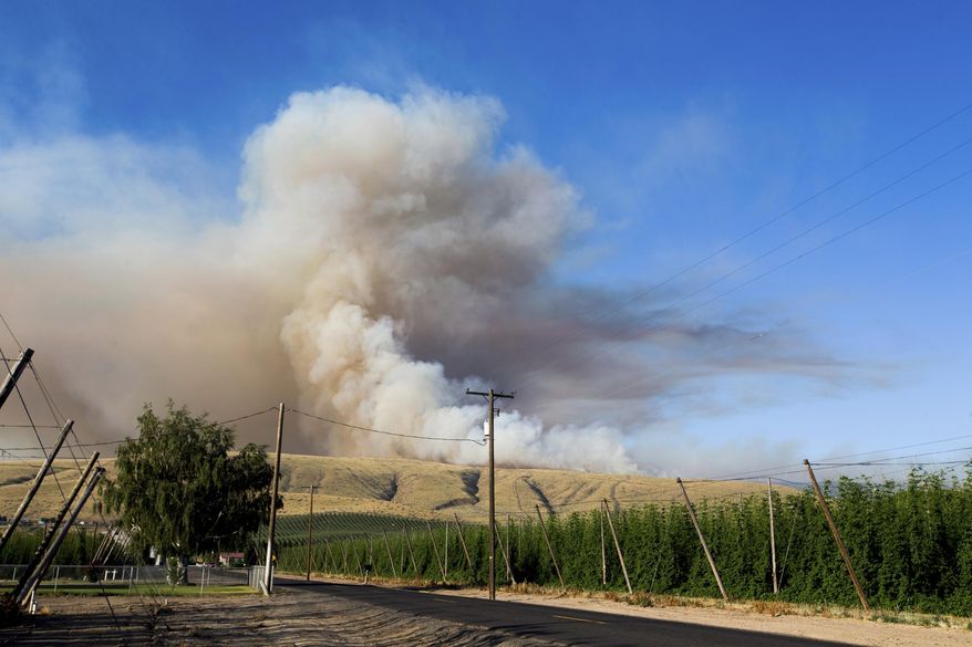 Smoke fills the sky as a brush fire burns on Rattlesnake Ridge in Moxee, Wash., on Thursday, July 6, 2017. The fire burned more than 5,500 acres of mostly grass and brush in less than 24 hours, and threatened about 30 homes. (Jake Parrish/Yakima Herald-Republic via AP)