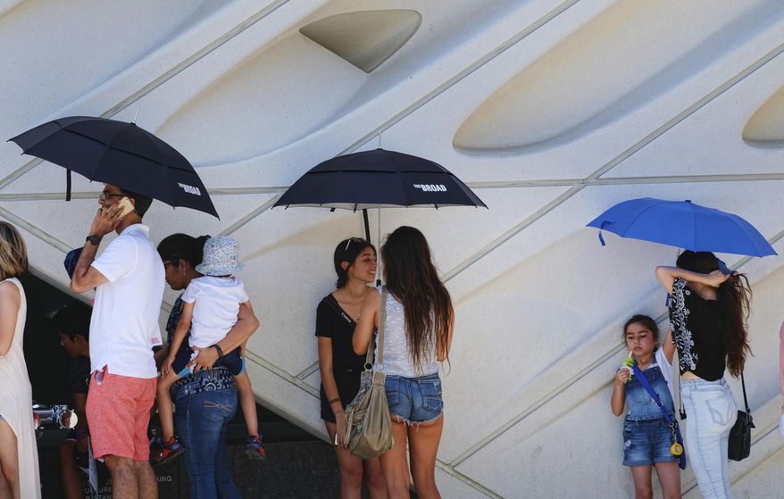 While waiting in line visitors at The Broad Museum, shade themselves from the afternoon heat in downtown Los Angeles on Friday, July 7, 2017. Southern California faces more blistering heat as firefighters around the state work to corral wildfires. The National Weather Service says high temperatures between 100 and 110 degrees will be common away from the coast Friday and Saturday while some coastal sections could see highs into the 90s. (AP Photo/Richard Vogel)