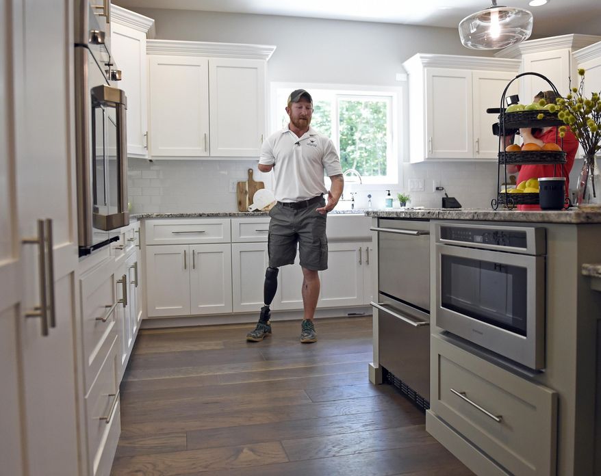 In this June 29, 2017 photo, retired U.S. Army Sgt. 1st Class Jared Bullock describes some of the modifications of the kitchen during a tour of his family's new smart home provided through the Gary Sinise Foundation following a dedication ceremony, outside of Carbondale, Ill. Bullock lost his right arm and right leg to an improvised explosive device in Afghanistan in 2013. The foundation established by Gary Sinise, an actor best known for his portrayal of Lt. Dan in the 1994 film "Forrest Gump", donates such homes to wounded veterans. (Byron Hetzler/The Southern, via AP)