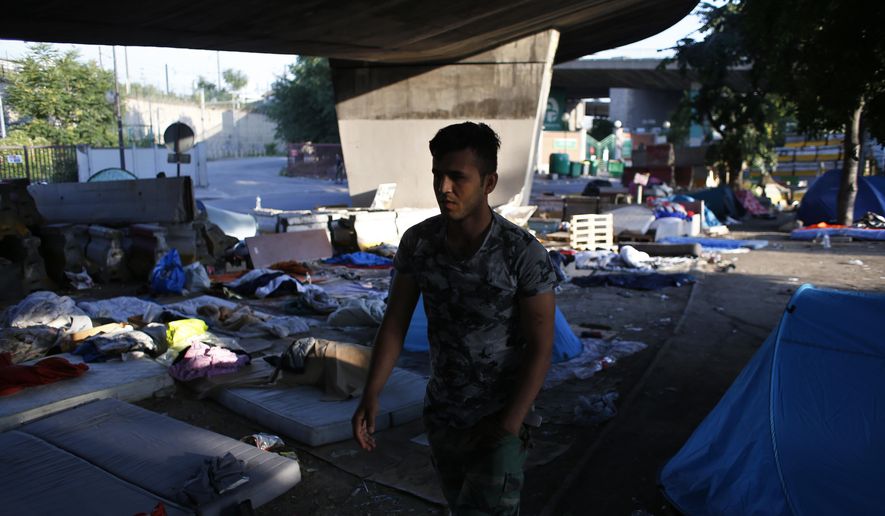 A migrant walks in a makeshift street camp to collect his matters before being evacuated, in Paris, Friday, July 7, 2017. Paris authorities are evacuating some 1,500 migrants from a makeshift street camp as Europe faces an upsurge in new arrivals. (AP Photo/Thibault Camus)