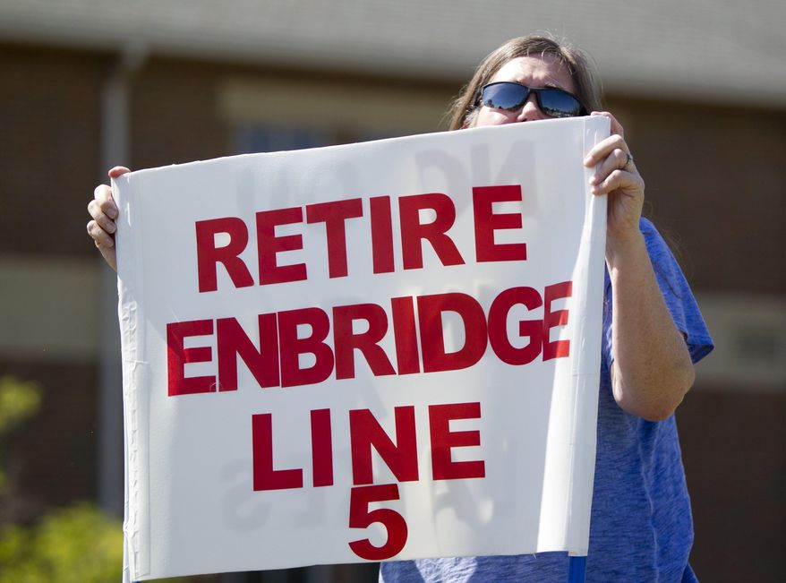 Lauren Sargent, of Ann Arbor, Mich. takes part in a protest before the Enbridge Line 5 pipeline public information session at Holt High School on Thursday, July 6, 2017 in Holt, Mich. The report by Dynamic Risk Assessment Systems, Inc. was prepared independently for the state of Michigan. (Cory Morse/The Grand Rapids Press via AP)