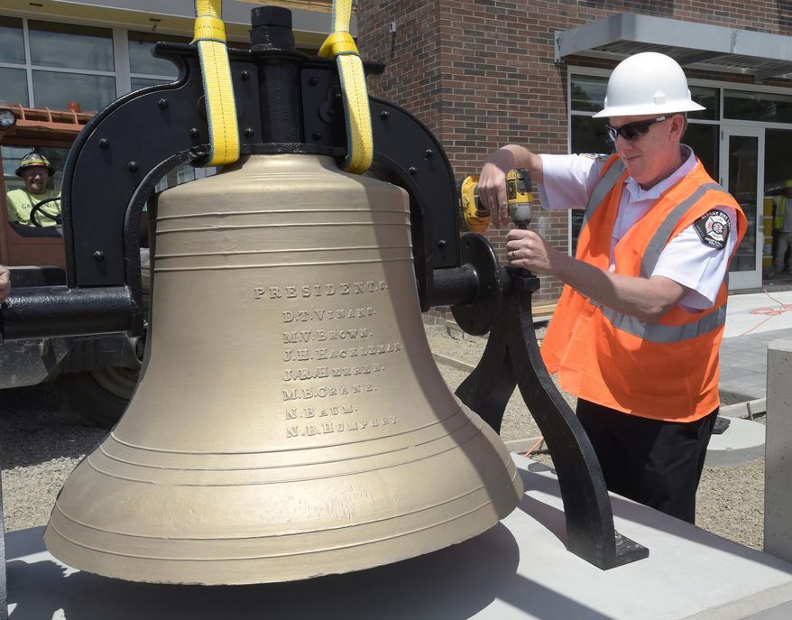 Fire Chief John Bradner fastens down the restored bell at the new Fire Station 11 in Albany, Ore., Wednesday June 28, 2017. (David Patton/Albany Democrat-Herald via AP)