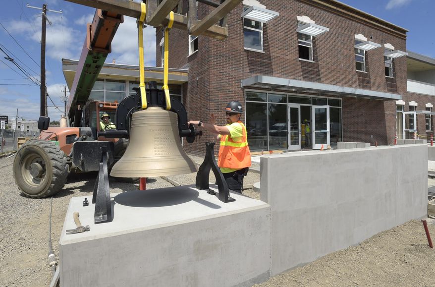 Project Superintendent James Lutz of Gerding Builders, right, guides the restored 1877 bell as forklift driver James Scott lowers it into place at the new Fire Station 11 in Albany, Ore., Wednesday June 28, 2017. (David Patton/Albany Democrat-Herald via AP)