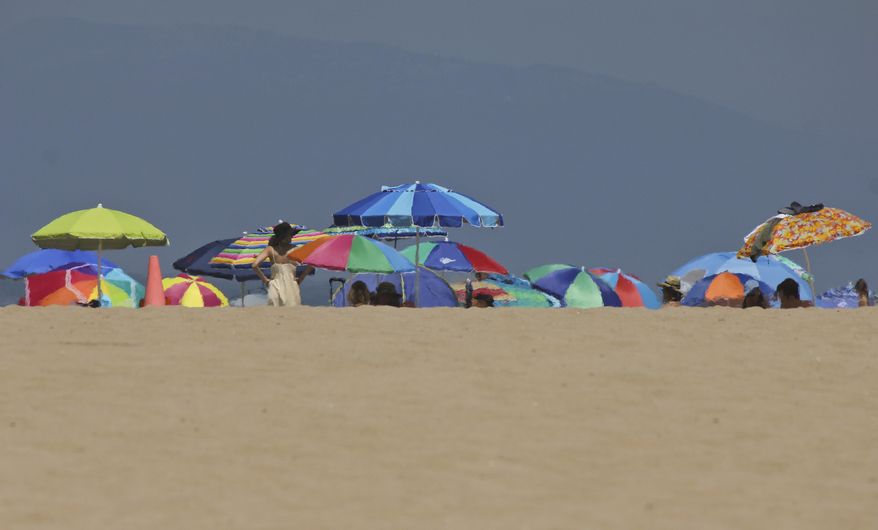 Heat rising from the sand ripples the image of umbrellas at Manhattan Beach, Calif., on Saturday, July 8, 2017. Crowds flocked to Southern California beaches to escape a triple-digit heat wave inland. Crowds flocked to beaches to seek relief from triple-digit heat across Southern California. An excessive heat wave in Southern California set records in several cities, breaking a mark set for the date in Los Angeles 131 years ago, the National Weather Service said. Around noon, the downtown temp spiked at 96 degrees, topping the 1886 record by a degree. (AP Photo/John Antczak)