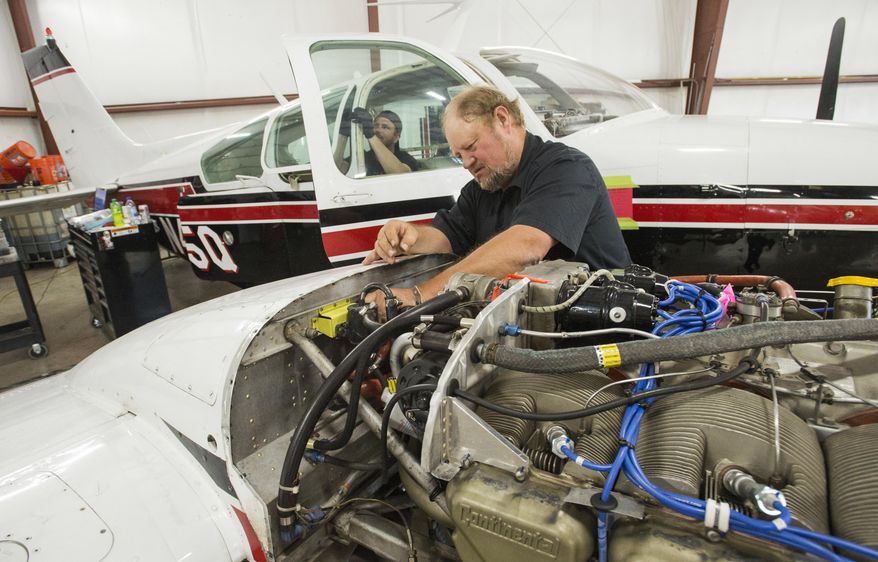 In this June 14, 2017 photo, Goose Bistline works on a Beechcraft Baron, twin-engined piston aircraft, that will be used in the Southern Utah University Flight School in Cedar City, Utah. The university bought new airplanes to try and lure students amid a pilot shortage. (Rick Egan/The Salt Lake Tribune via AP)