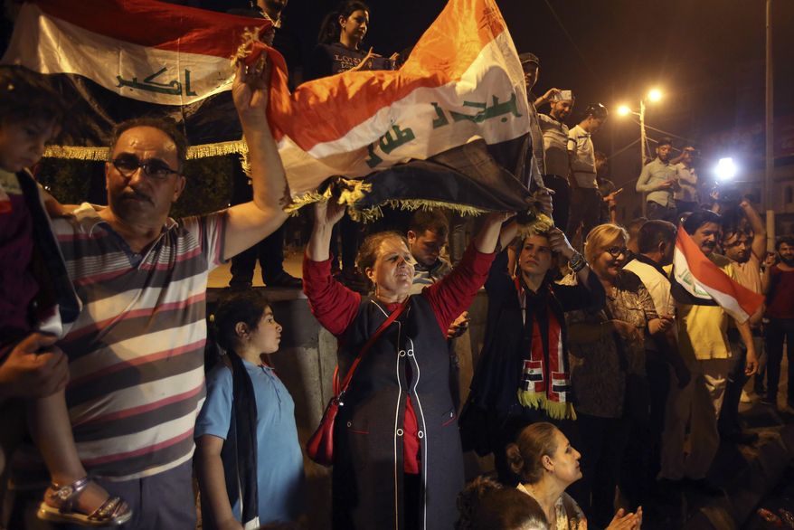 Iraqis celebrate in Tahrir square while holding national flags as they wait for the final announcement of the defeat of the Islamic state militants, in Baghdad, Iraq, Sunday, July 9, 2017. Backed by the U.S.-led coalition, Iraq launched the operation to retake Mosul from Islamic State militants in October. (AP Photo/Karim Kadim)
