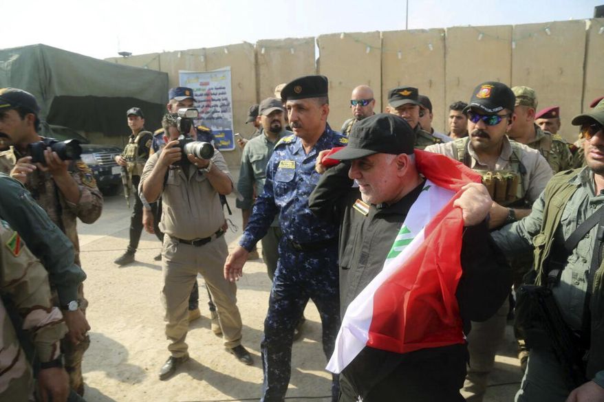 Iraq&#39;s Prime Minister Haider al-Abadi, center, holds a national flag upon his arrival to Mosul, Iraq, Sunday, July 9, 2017. Backed by the U.S.-led coalition, Iraq launched the operation to retake Mosul from Islamic State militants in October. (Iraqi Federal Police Press Office via AP)