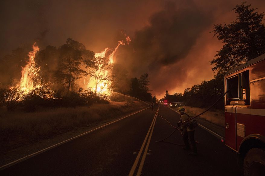 A firefighter battles a wildfire as it threatens to jump a street near Oroville, Calif., on Saturday, July 8, 2017. Evening winds drove the fire through several neighborhoods leveling homes in its path. (AP Photo/Noah Berger)