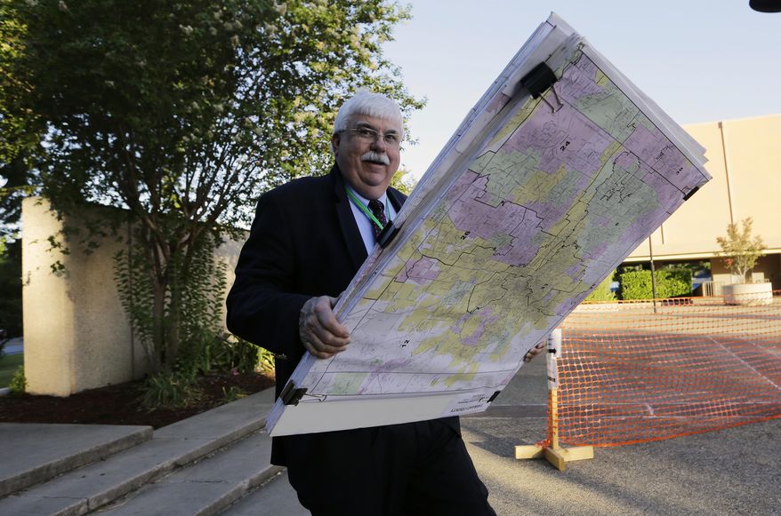 ADDS NAME OF MAN AS RUSS TIDWELL - Russ Tidwell, a former lobbyist who is helping minority rights groups sue Texas over Republican-drawn voting maps holds a set of maps as he makes his way to the federal court house, Monday, July 10, 2017, in San Antonio, where a redistricting trial is set to begin. Federal courts earlier this year found that Texas passed election laws to purposefully discriminate against Hispanic and black voters and the trial starting Monday could redraw Texas voting maps before 2018 and bolster Democratic efforts to reclaim Congress. (AP Photo/Eric Gay)