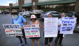 From left, Gary Mogensen, Barbara Ventarola, Carrie Barker-Carson and Karen Louden hold signs as protesters from several central Florida voter advocacy groups demonstrate in front of the Orange County Supervisor of Elections office, in Orlando, Fla., Monday, July 10, 2017. The groups are protesting the support by Florida governor Rick Scott of the voter fraud probe by President Donald Trump that would collect personal voter registration data. (Joe Burbank/Orlando Sentinel via AP)