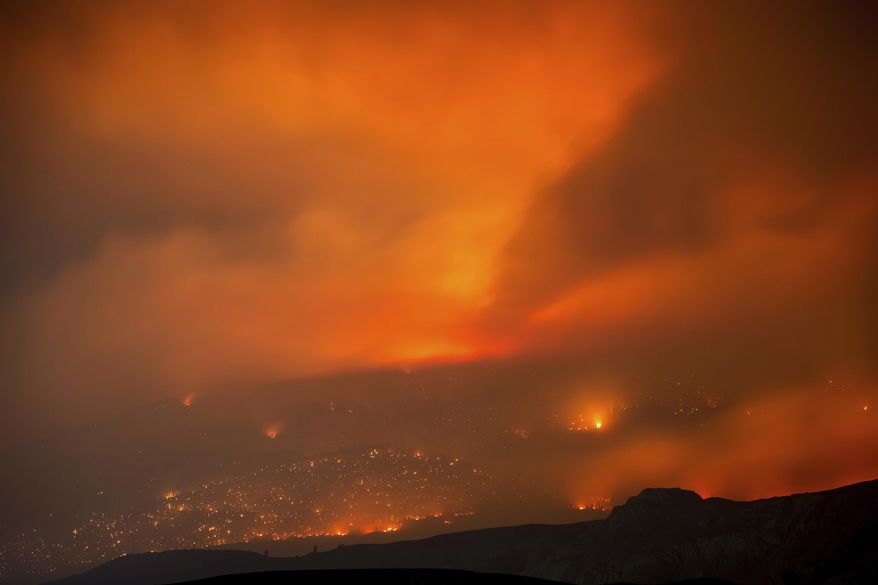 A wildfire burns on a mountain in the distance east of Cache Creek, British Columbia, early Monday, July 10, 2017. Wildfires barreled across the baking landscape of the western U.S. and Canada, destroying homes and forcing thousands of residents to flee. (Darryl Dyck/The Canadian Press via AP)