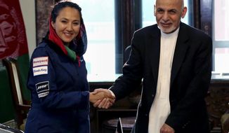 In this Monday, July 10, 2017 photo, Afghan President Ashraf Ghani shakes hands with Afghan-American female pilot Shaesta Waiz at the Presidential Palace in Kabul, Afghanistan. Waiz, who is on a solo flight around the world to inspire young women, has taken a detour to visit Afghanistan. Waiz left her single-engine plane in Dubai, the United Arab Emirates, to take a commercial flight to Kabul where she landed on Monday night. Waiz began her journey in May and has since stopped in 11 countries, with eight more to go. (Afghan Presidential Palace via AP)