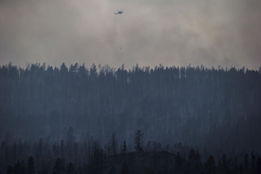 A helicopter is used to battle a wildfire burning on the top of a mountain near Ashcroft, British Columbia, Monday, July 10, 2017. Across the border in Canada, crews contended with more than 200 wildfires in British Columbia that have forced thousands to flee and destroyed dozens of buildings, including several homes and two airport hangars. (Darryl Dyck/The Canadian Press via AP)