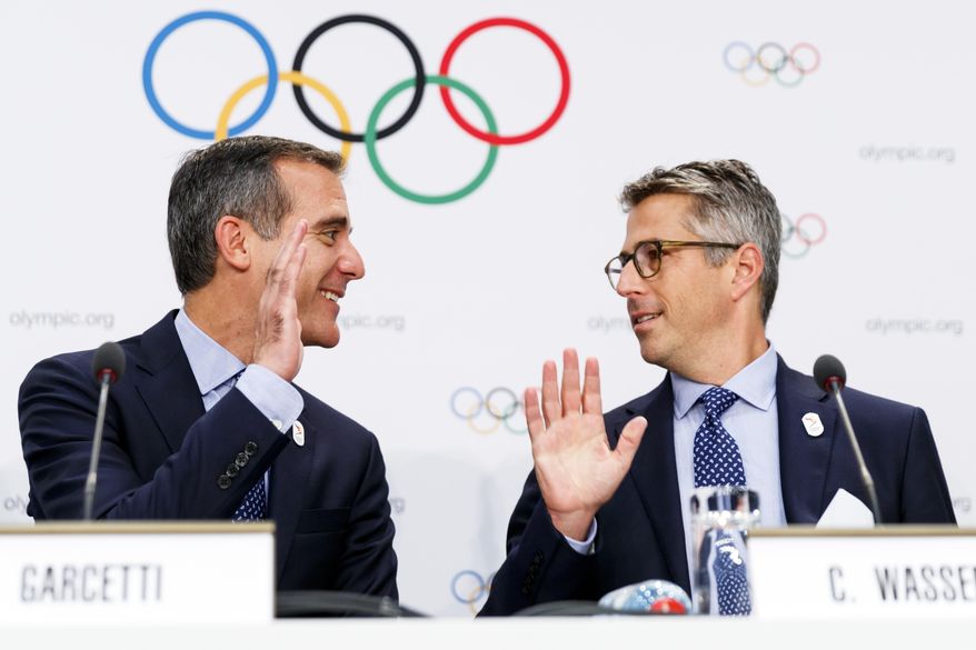 Eric Garcetti Mayor of Los Angeles, left, and Casey Wasserman chairman of Los Angeles 2024, right, high fived during a press conference after the presentation of Los Angeles 2024 Candidate City Briefing for International Olympic Committee (IOC) Members, at the SwissTech Convention Centre, in Lausanne, Switzerland, Tuesday, July 11, 2017. (Valentin Flauraud/Keystone via AP)