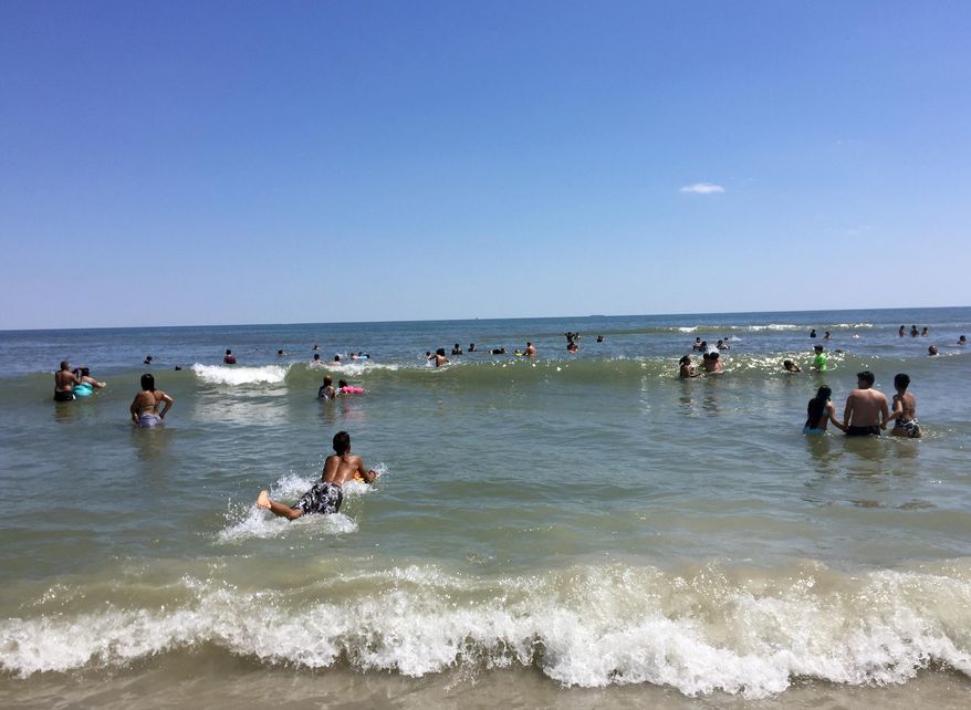 This July 9, 2017 photo shows a beach in the Rockaways, in the Queens borough of New York, on the Atlantic Ocean, with some beach-goers using body boards to ride the waves. A new ferry that travels between Lower Manhattan and the Rockaways has made it easier to get to the beach, which is known for its crashing surf. (AP Photo/Beth J. Harpaz)