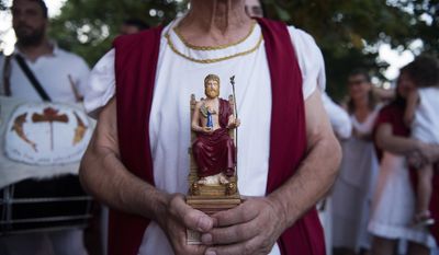 In this on Friday, July 7, 2017 photo, a man holds the statue of ancient Greek god Zeus, before a torch-lit procession at the northern Greek village of Litohoro. Devotees of ancient Greece&#x27;s religion and culture gather each July at the foot of Mount Olympus to hold a series of events, ceremonies and seminars. (AP Photo/Giannis Papanikos)