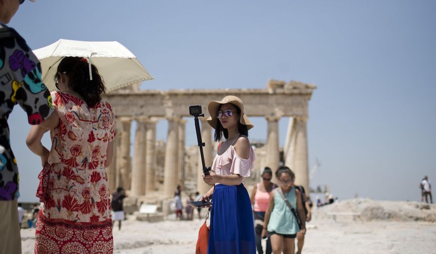 A tourist takes a selfie in front of the fifth century BC Parthenon temple at the Acropolis hill in Athens, Wednesday, July 12, 2017. Greece's Culture Ministry says that all Greek archaeological sites, including Athens' internationally famed Acropolis, will shut during the hottest hours of the day from Wednesday, due to a predicted heat wave. (AP Photo/Petros Giannakouris)