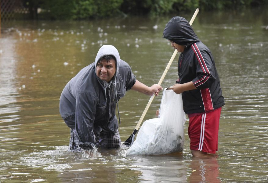 Jorge Morales and his son Ariel, try to clear drains in front of his home in Mundelein, Ill., Wednesday morning, July 12, 2017. Flooding hit the Chicago suburb as storms moved through the area. (Paul Valade/Daily Herald via AP)