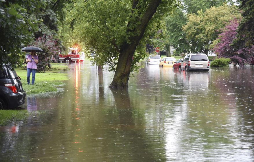 A woman stands by a flooded street Wednesday morning, July 12, 2017, in Mundelein, Ill. Flooding hit the Chicago suburb as storms moved through the area. (Paul Valade/Daily Herald via AP)