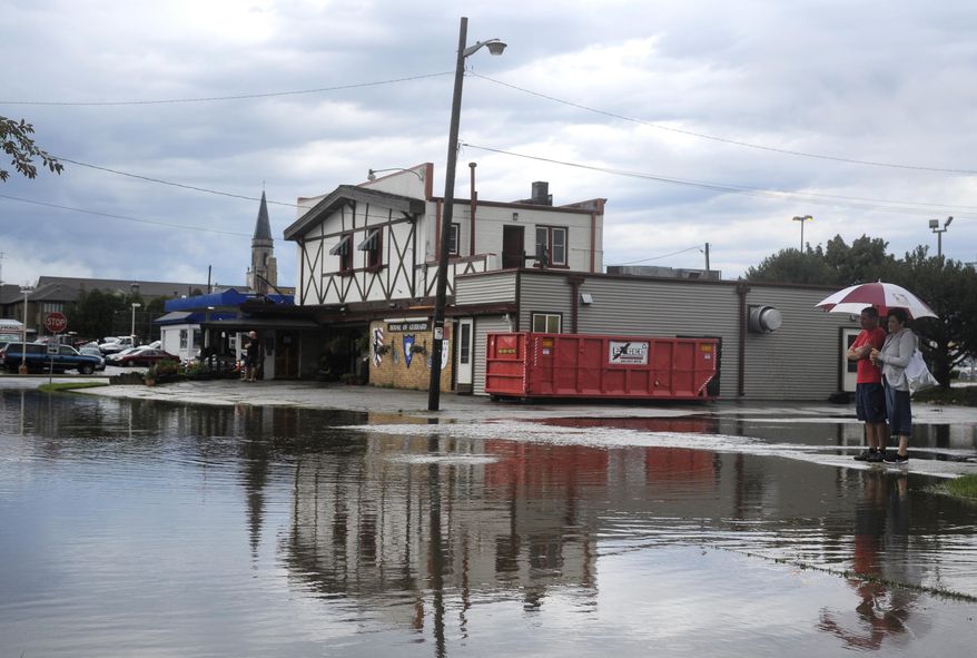 Passerbys look at a flooded intersection in Kenosha, Wis., Wednesday morning, July 12, 2017. Heavy thunderstorms are causing travel difficulties around southern Wisconsin because of flooding. Numerous municipalities are dealing with impassable streets. (Sean Krajacic/The Kenosha News via AP)