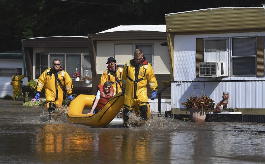 Members of Pleasant Prairie, Wis., and Somers, Wis., Fire Departments assist Mary Knoebel from her trailer during flooding in Pleasant Prairie, Wis., Wednesday, July 12, 2017. Flooding has forced the evacuation of the mobile home park in southeastern Wisconsin. (Bill Siel/The Kenosha News via AP)