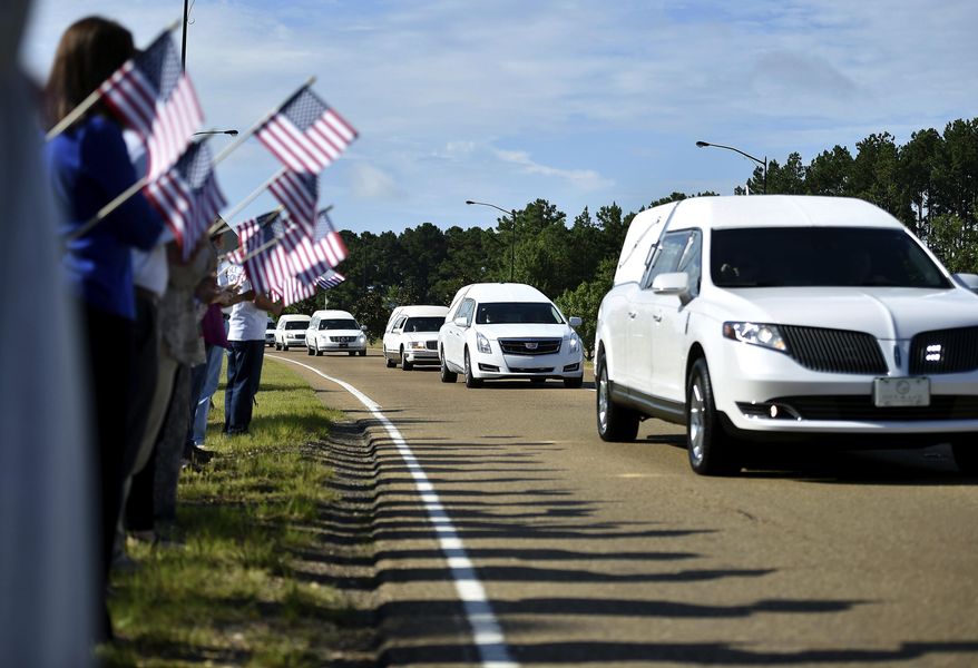 Supporters hold American flags on the side of Airport Road in Jackson, Mississippi, Thursday, July 13, 2017, as hearses carry the remains of the 16 service members who died in a plane crash in Leflore County, Mississippi Monday to the Air National Guard base for their final flights home. (Justin Sellers/The Clarion-Ledger via AP)