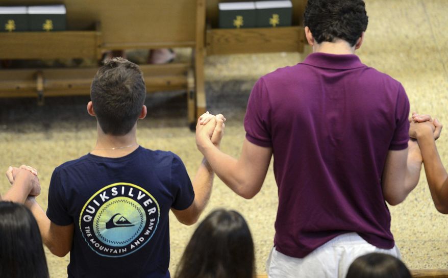 Friends and classmates of student Abigail Bastien pray together at St. Mary's Catholic Church Thursday evening, July 13, 2017, in Sandusky, Ohio. Johns Hopkins University officials say Bastien found dead Thursday morning near the Maryland campus was a rising sophomore and member of the track and field team. Police say they are investigating, but there were no obvious signs of foul play at the scene. (Jilly Burns/The Sandusky Register via AP)