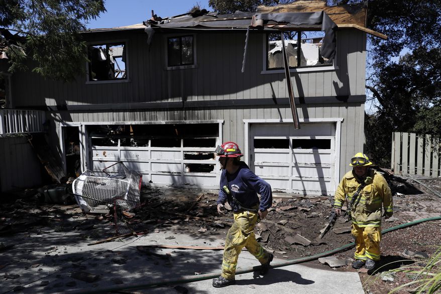 Firefighters Daniel Lizardo, right, and Victor Velasquez walk in front of a fire-ravaged home Wednesday, July 12, 2017, in San Jose, Calif. Relief was arriving after a rough stretch of wildfires all around the U.S. West, with firefighters slowly surrounding once-fierce blazes and evacuees starting to stream back home. (AP Photo/Marcio Jose Sanchez)