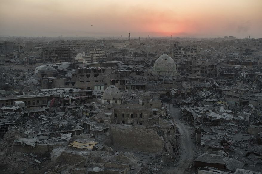 In this July 11, 2017 photo, the sun sets behind destroyed buildings in the west side of Mosul, Iraq. The 9-month fight to defeat the Islamic State group in Mosul ended in a crescendo of devastation: bombardment that damaged or destroyed a third of its historic Old City in just three weeks. The cost of uprooting the militants was the destruction of large swaths of Iraq’s second largest city, leaving a population that is displaced, exhausted and potentially embittered if there is no reconstruction. (AP Photo/Felipe Dana)