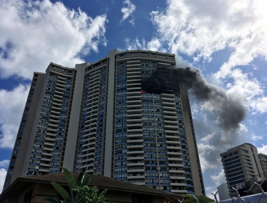 Smoke billows from a high-rise apartment building in Honolulu, Friday, July 14, 2017. Dozens of firefighters are battling the multiple-alarm fire at Marco Polo apartments that Honolulu Fire Department spokesman Capt. David Jenkins said started on the 26th floor and has spread to other units. (AP Photo/Audrey McAvoy)