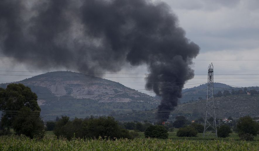 In this July 11, 2017 photo, smoke rises from a warehouse storing stolen fuel near Tepeaca, Puebla state, Mexico. Authorities couldn't enter the area to fight the blaze because they risked a confrontation with local villagers. "They usually try to put the fires out themselves," said Assistant Public Safety Secretary Jose Tlachi. (AP Photo/Eduardo Verdugo)
