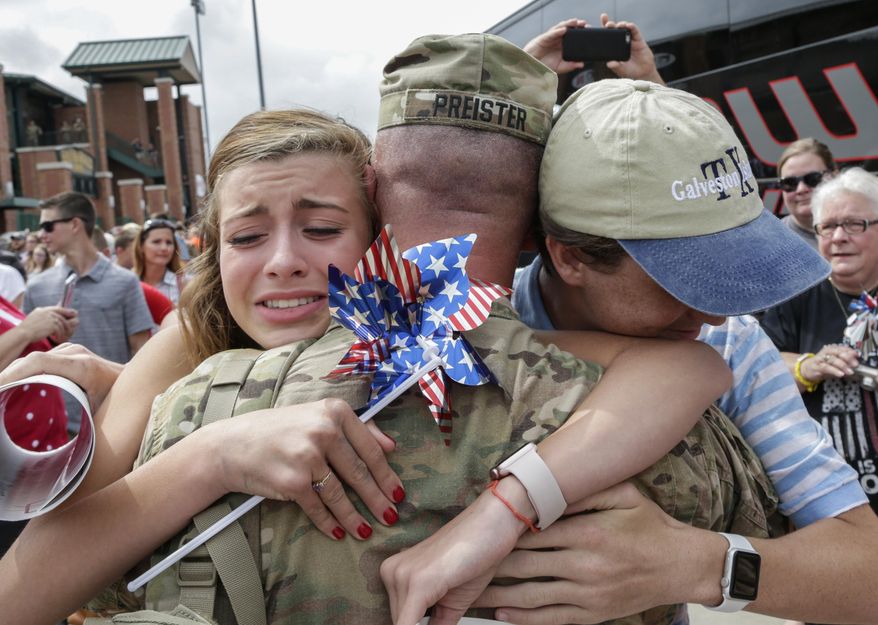 Bella Preister, left, of Omaha, Neb., hugs her father, Maj. Jeremy Preister, as he steps off a bus to a welcoming ceremony, Thursday, July 13, 2017, in Lincoln, Neb. About 90 Nebraska Army National Guard soldiers, members of the 1st Infantry Division Main Command Post-Operational Detachment, met their families for the first time after spending the last 9 months deployed in Iraq. (AP Photo/Nati Harnik)