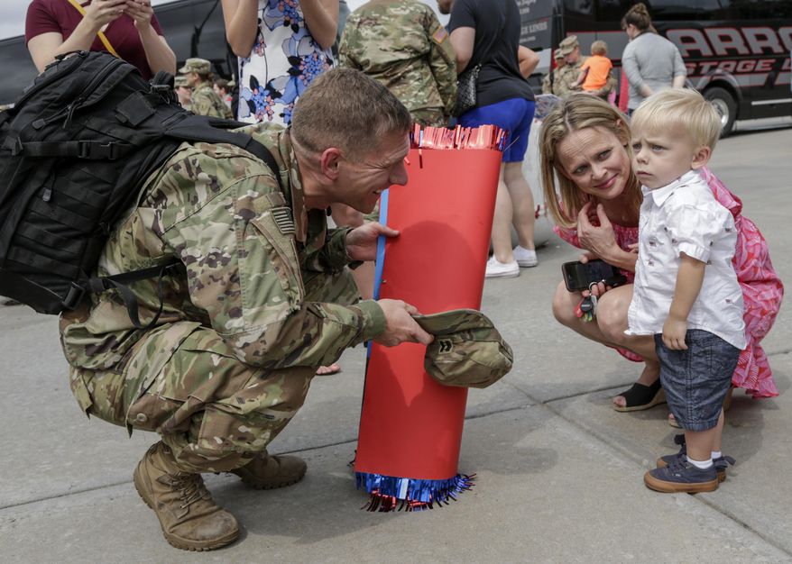 Capt. Steve Preston tries to get re-acquainted with his son Tommy as his wife Amber looks on, at a welcoming ceremony in Lincoln, Neb., Thursday, July 13, 2017, for about 90 Nebraska Army National Guard soldiers, members of the 1st Infantry Division Main Command Post-Operational Detachment, who had met their families for the first time after spending the last 9 months deployed in Iraq. (AP Photo/Nati Harnik)