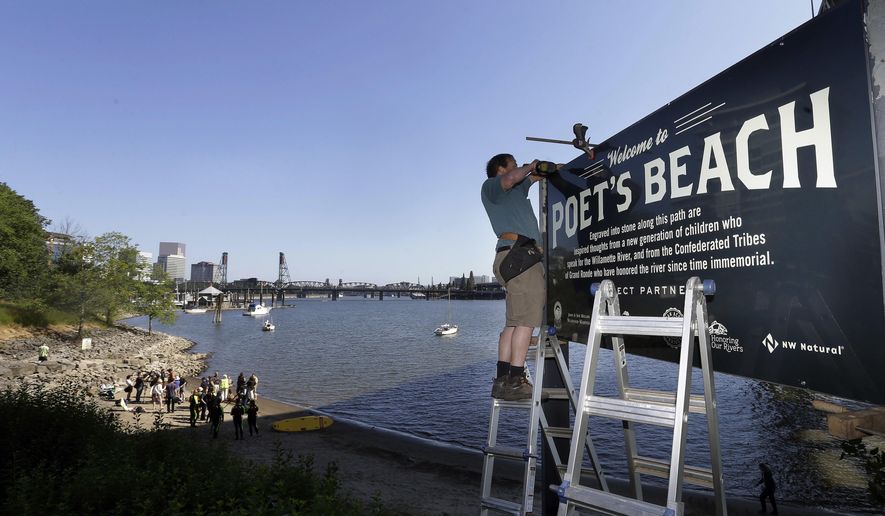 In this Thursday, July 6, 2017 photo, Curt Ellsworth puts up a sign at a section of newly formed beach, named Poet's Beach, on the Willamette River in downtown Portland, Ore. Portland is well-known as a tree-hugging, outdoorsy city, but the river that powers through its downtown has never been part of that green reputation. For decades, residents have been repulsed by the idea of swimming in the Willamette River because of weekly sewage overflows that created a bacterial stew. Now, the recent completion of a $1.4 billion sewage pipe has flushed those worries - and the river once shunned by swimmers is enjoying a rapid renaissance. (AP Photo/Don Ryan)