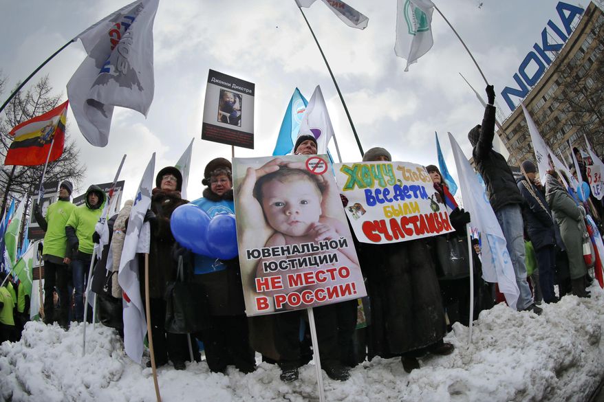 FILE - In this Saturday, March 2, 2013 file photo, demonstrators hold posters reading "There is no place for juvenile justice in Russia," "I want all children be happy" during a rally in Moscow to support the ban on U.S. adoptions of Russian children. More than four years after it was imposed, Russia's ban on adoptions by Americans is back in the news, rekindling frustration and sadness among some of those affected by it. (AP Photo/Alexander Zemlianichenko)