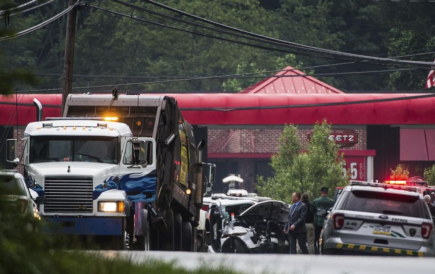 Investigators examine the scene where a garbage truck and a Pennsylvania state trooper vehicle collided just before the fork of Route 711 and 271 in Ligonier Township, Pa., Friday, July 14, 2017. A state trooper died and another was injured in the crash. The conditions of the injured trooper and the garbage truck driver were not immediately known (Shane Dunlap/Pittsburgh Tribune-Review via AP)