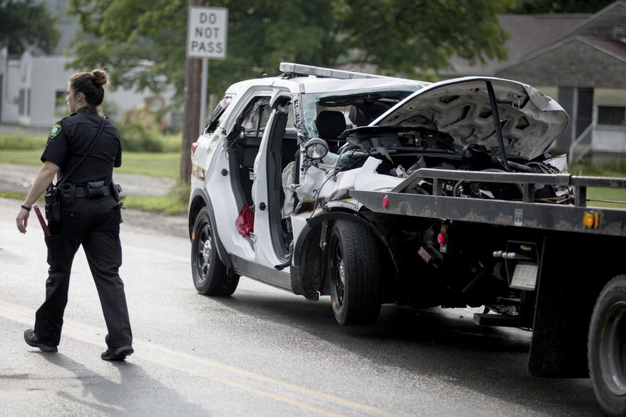 An officer walks by the wreckage of a Pennsylvania State Trooper vehicle after a collision with a garbage truck in Ligonier Township, Pa., Friday, July 14, 2017. A state trooper died and another was injured in the crash. The conditions of the injured trooper and the garbage truck driver were not immediately known (Alex Driehaus//Pittsburgh Post-Gazette via AP)