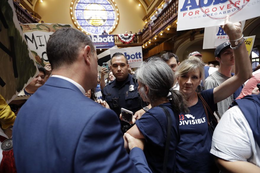 Protesters are led out of an event where Texas Gov. Greg Abbott announced his bid for re-election, Friday, July 14, 2017, in San Antonio. (AP Photo/Eric Gay)