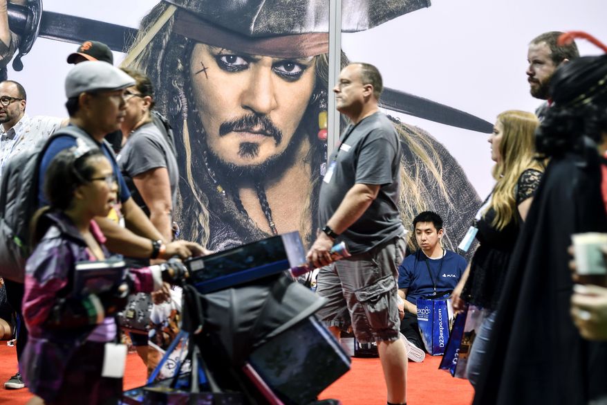 Visitors walk past a picture of Disney character Captain Jack Sparrow during the D23 Expo at the Anaheim Convention Center in Anaheim, Calif., on Friday, July 14, 2017. (Jeff Gritchen/The Orange County Register via AP)