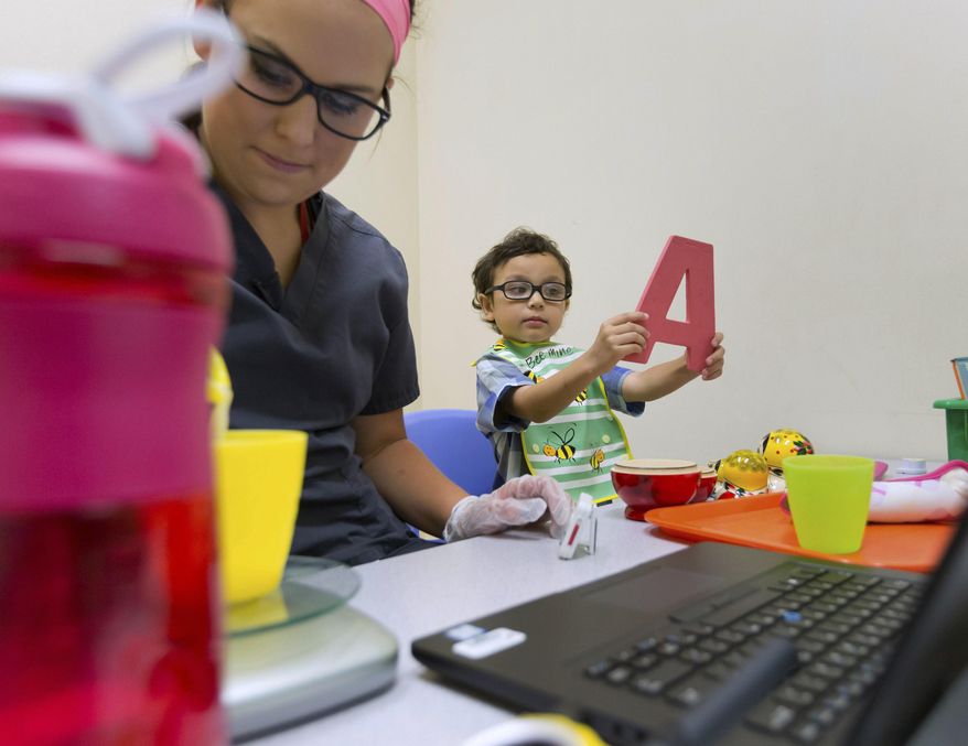 In a Wednesday, June 28, 2017, photo, Mason Plock-Sisoutho holds the letter A while working on his self-drinking skills with behavioral therapist Taya Zagurski, in Omaha, Neb. At the start of 2016, Mason became the first child enrolled in the Munroe-Meyer Institute's SEEDS program (Starting Early: Eating and Developmental Skills). The program, a combination of feeding therapy and early intervention services, is designed for children with autism spectrum disorder and developmental disabilities. (Kent Sievers/Omaha World-Herald via AP) **FILE**