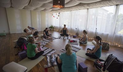 ADVANCE FOR USE SATURDAY, JULY 15 - In this Friday, June 30, 2017 photo, Daniele Strawmyre, center, top in all black, leads participants in a postpartum yoga class at Vancouver Wellness Studio in Vancouver, Wash. (Amanda Cowan/The Columbian via AP)
