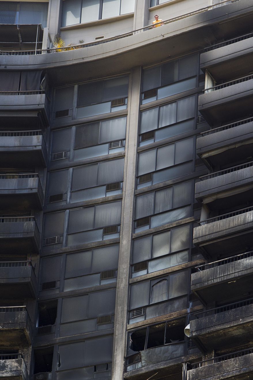 A man looks off his balcony at the the damage left from a deadly fire that destroyed several floors of the Marco Polo residence, Saturday, July 15, 2017, in Honolulu. A fire broke out Friday afternoon in a unit on the 26th floor, where all three of the dead were found, Fire Chief Manuel Neves said. (AP Photo/Marco Garcia)
