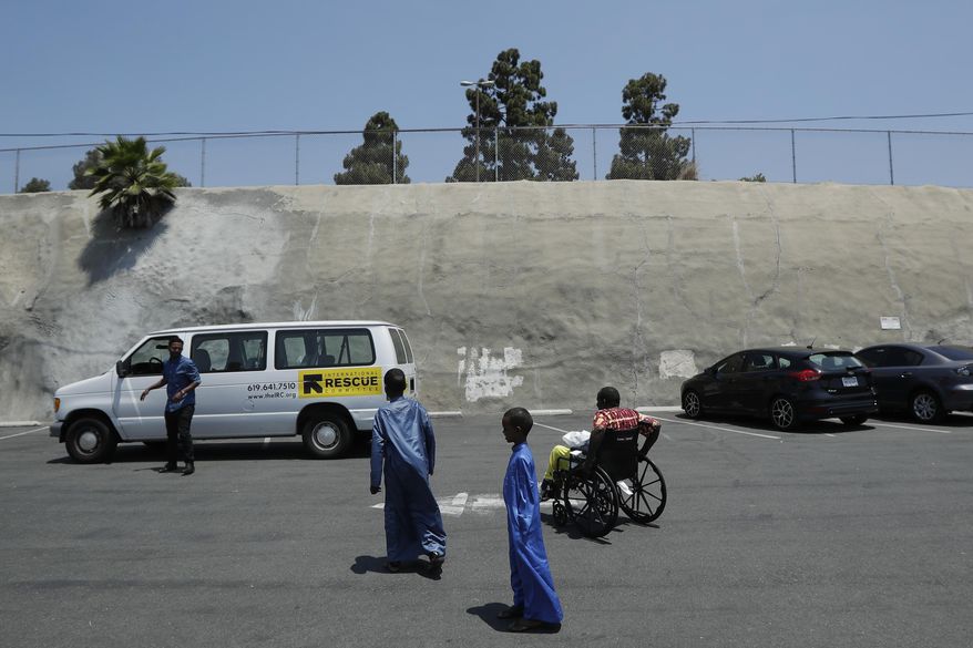 FILE - In this July 6, 2017, file photo, Ali Said, of Somalia, right, leaves a center for refugees with his two sons, as refugee caseworker Mohamed Yassin, left, waits by a van in San Diego. A federal judge in Hawaii further weakened the already-diluted travel ban Thursday, July 13, 2017, by vastly expanding the list of U.S. family relationships that visitors from six Muslim-majority countries can use to get into the country. (AP Photo/Gregory Bull, File)